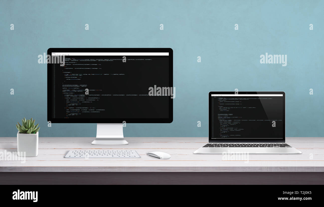 L'ordinateur de bureau et ordinateur portable sur un bureau avec l'éditeur de programmation sur l'écran. Concept de studio de programmation. Banque D'Images