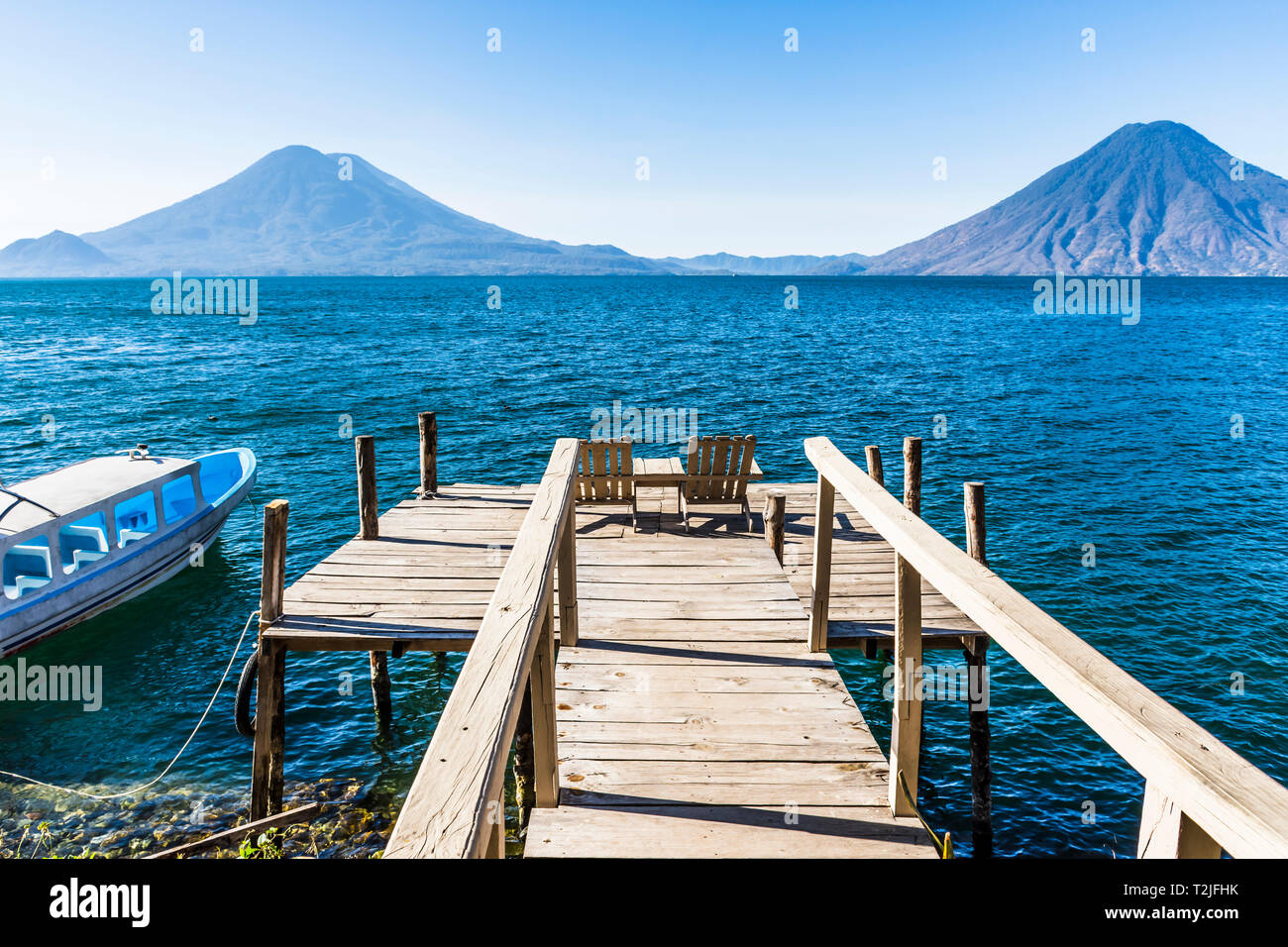 Vue depuis la jetée en bois avec des sièges à travers le lac Atitlan à Atitlan, Toliman et San Pedro les volcans de hautes terres du Guatemala, en Amérique centrale Banque D'Images