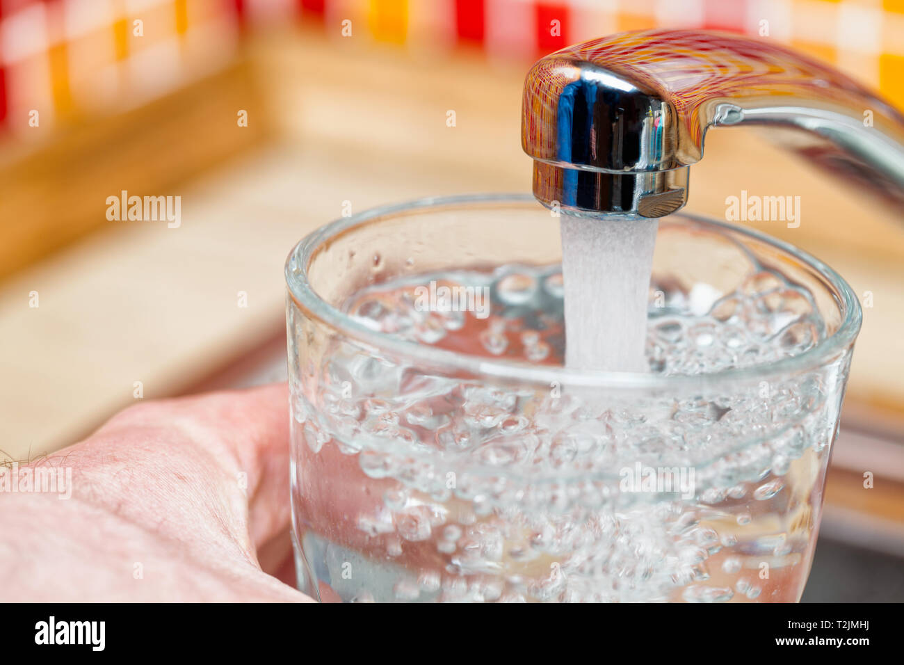 Libre tourné d'un homme de servir un verre d'eau douce dans un robinet de cuisine Banque D'Images