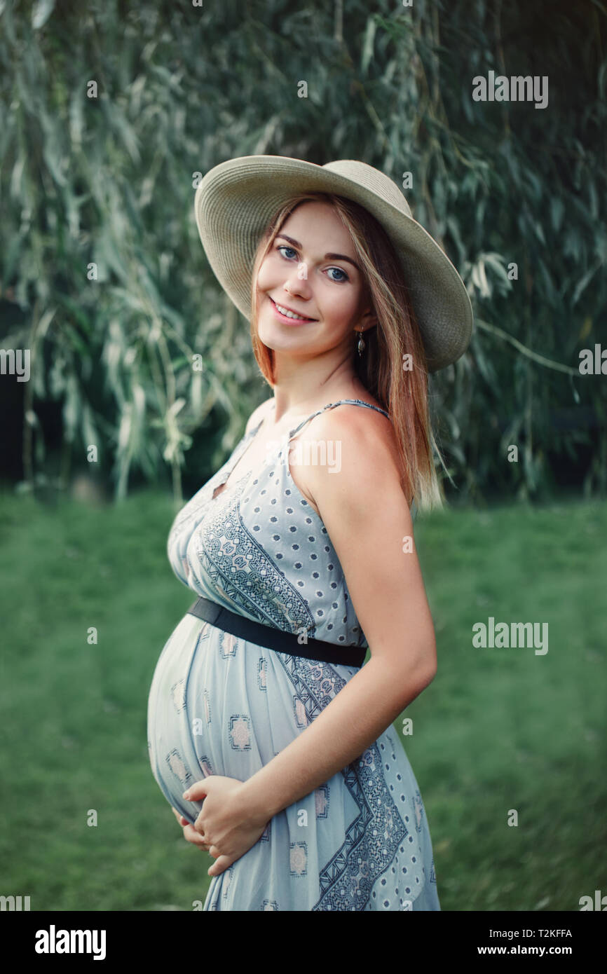 Heureux sain la grossesse et la maternité. Portrait of pregnant Caucasian  woman wearing long robe bleue et chapeau rustique de pays en dehors du  parc. Beau Photo Stock - Alamy
