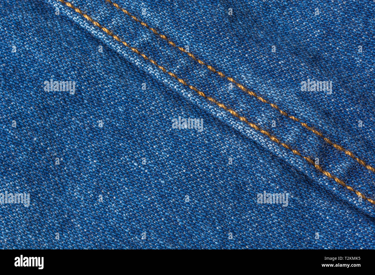 Gros plan en tissu denim bleu, avec motif de déformation et de trame et coutures orange. Ligne cousue, ligne de points de suture. Banque D'Images