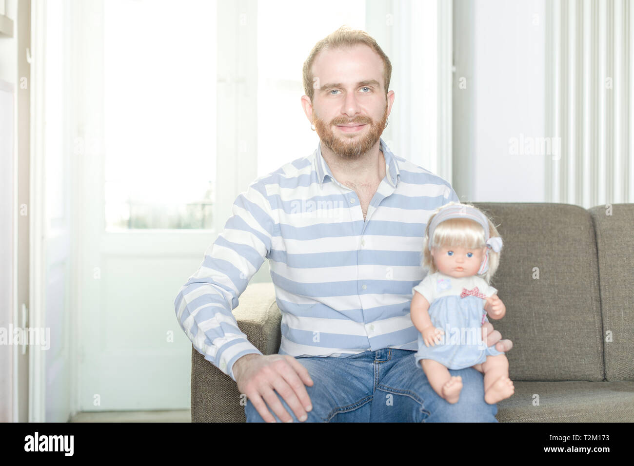Smiling Redhead homme sur une table avec une poupée assise sur son genou Banque D'Images