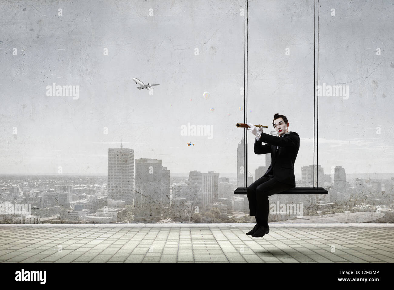 Mime l'homme en costume noir assis sur swing. Technique mixte Banque D'Images