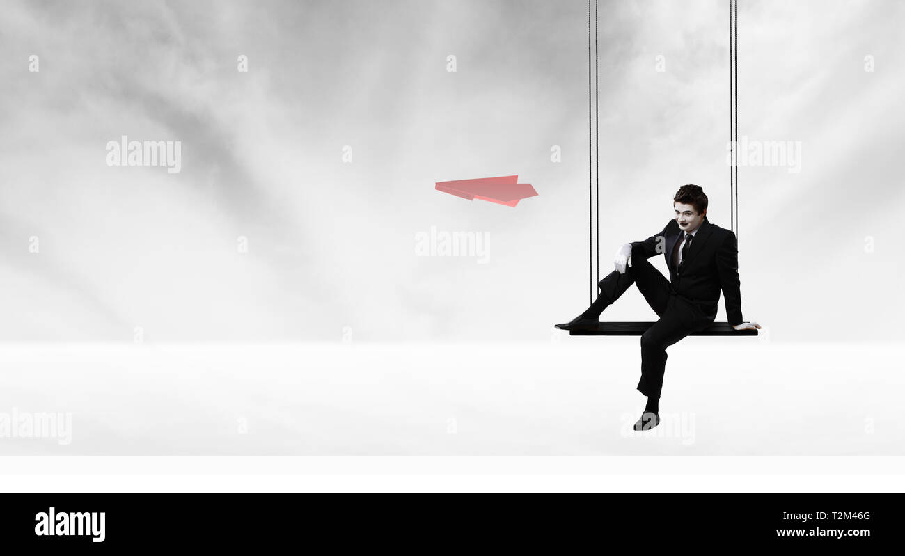 Mime l'homme en costume noir assis sur swing. Technique mixte Banque D'Images