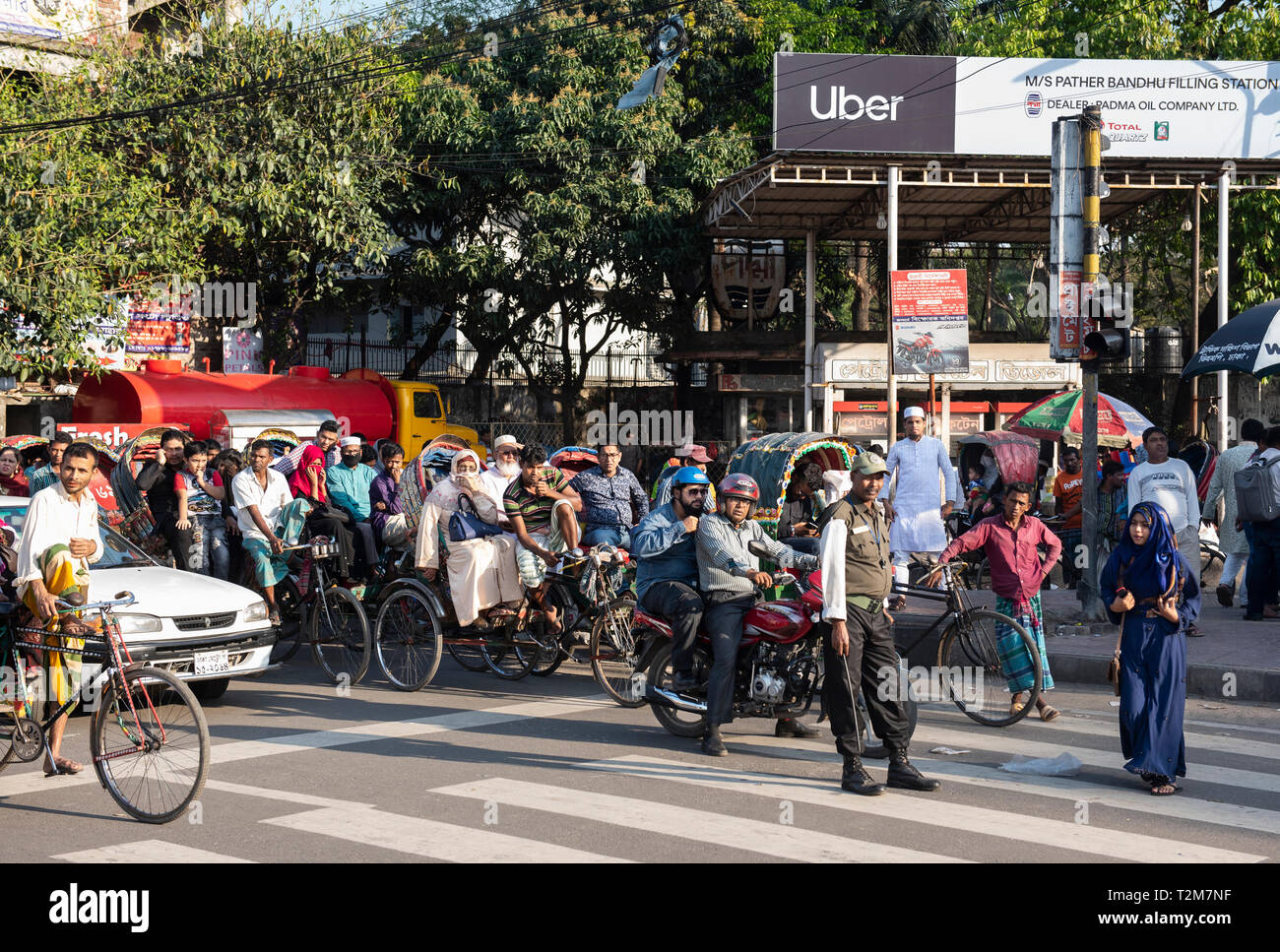 Sont considérés de banlieue en attente à un feu de circulation à côté d'une publicité pour American online le covoiturage et le transport de l'entreprise réseau Uber à Dhaka. Banque D'Images