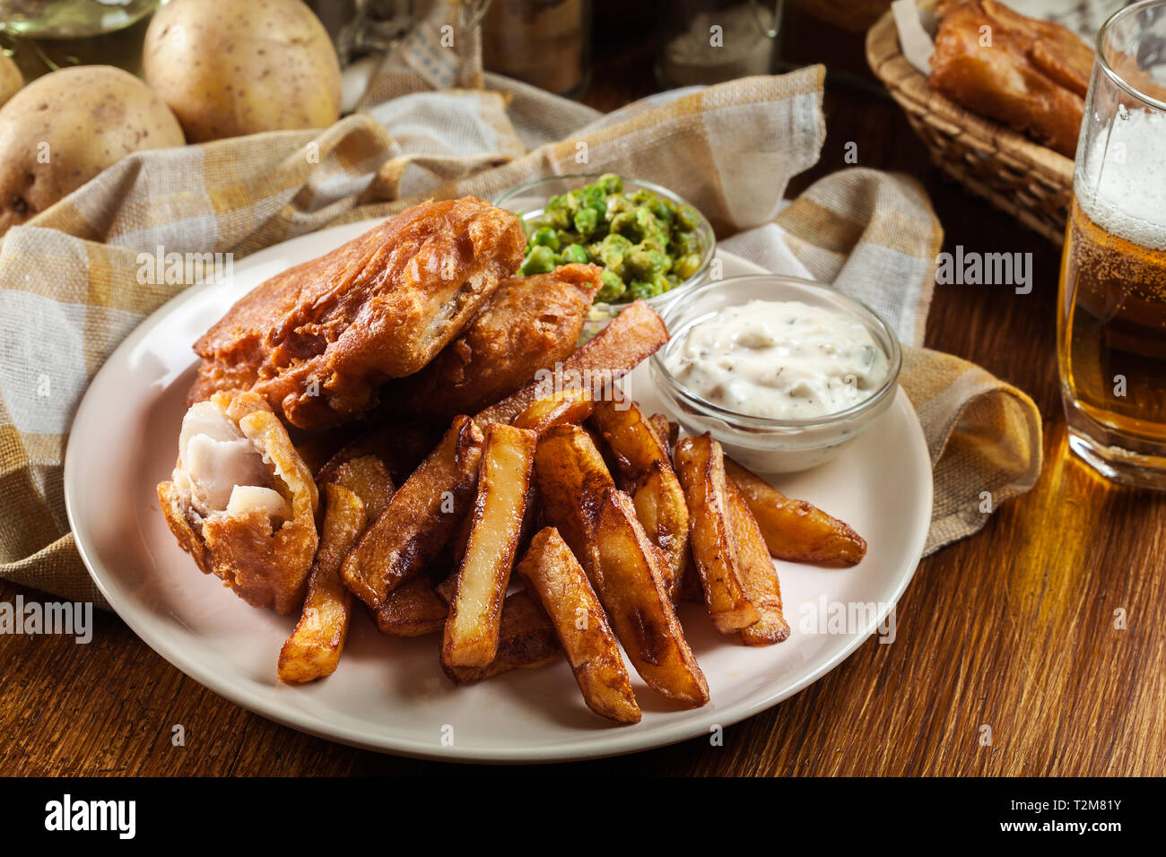 Le poisson dans la pâte traditionnelle de la bière et des frites avec de petits pois et sauce tartare Banque D'Images