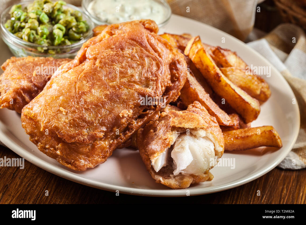 Le poisson dans la pâte traditionnelle de la bière et des frites avec de petits pois et sauce tartare Banque D'Images