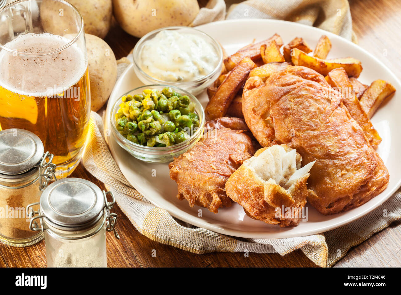 Le poisson dans la pâte traditionnelle de la bière et des frites avec de petits pois et sauce tartare Banque D'Images