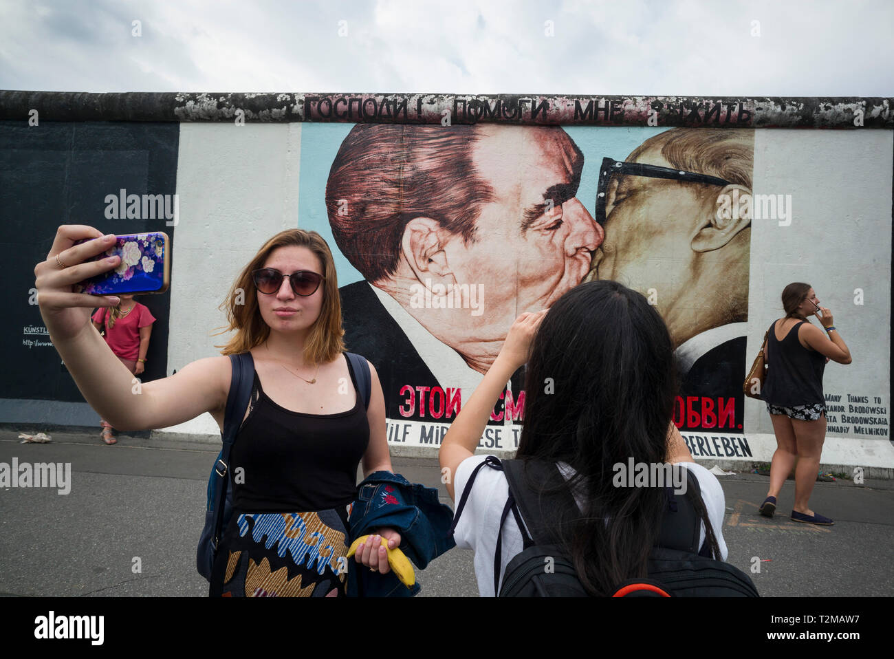 Berlin. L'Allemagne. Les touristes posent pour des photos en face de l'une des autres sections du Mur de Berlin à l'East Side Gallery. Des touristes posent pour ph Banque D'Images