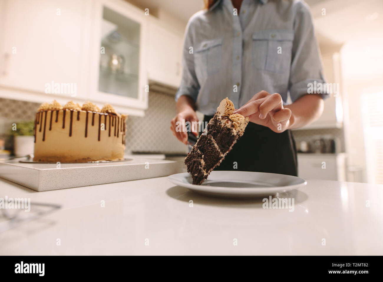Close up of female chef de placer une tranche de gâteau sur la plaque avec un couteau. Chef de la préparation d'un délicieux dessert. Banque D'Images