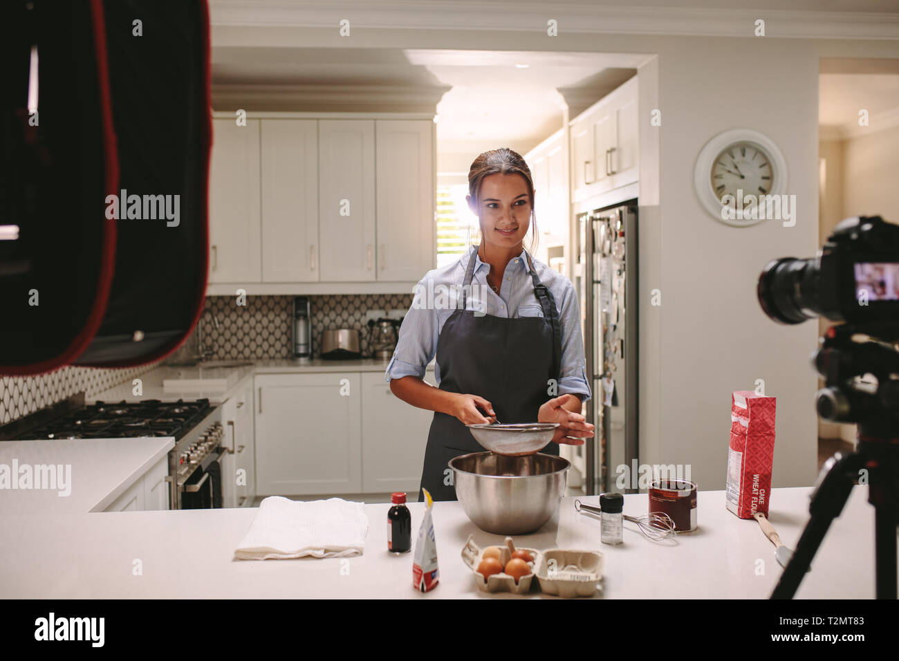 Femme préparant des gâteaux dans la cuisine et l'enregistrement vidéo sur un appareil photo. Chef pâtissier enregistrement de contenu pour l'aliment vlog. Banque D'Images
