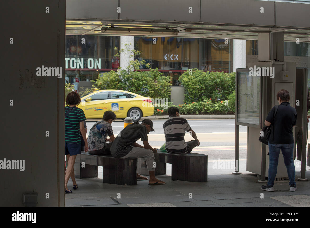 Les gens attendent à un arrêt d'autobus dans le centre de Singapour Banque D'Images