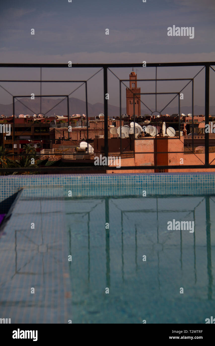Maroc Marrakech piscine sur le toit avec piscine vue locale Réflexion et clocher de l'Église et Paraboles a mis en évidence par la lumière du soleil Banque D'Images