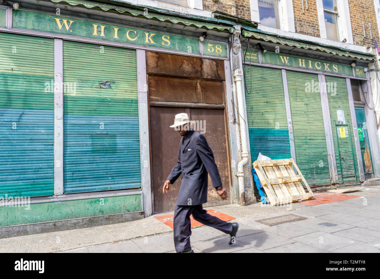 Man (motion floue) marchant devant fermé boutique à Golborne Road, Notting Hill. Banque D'Images