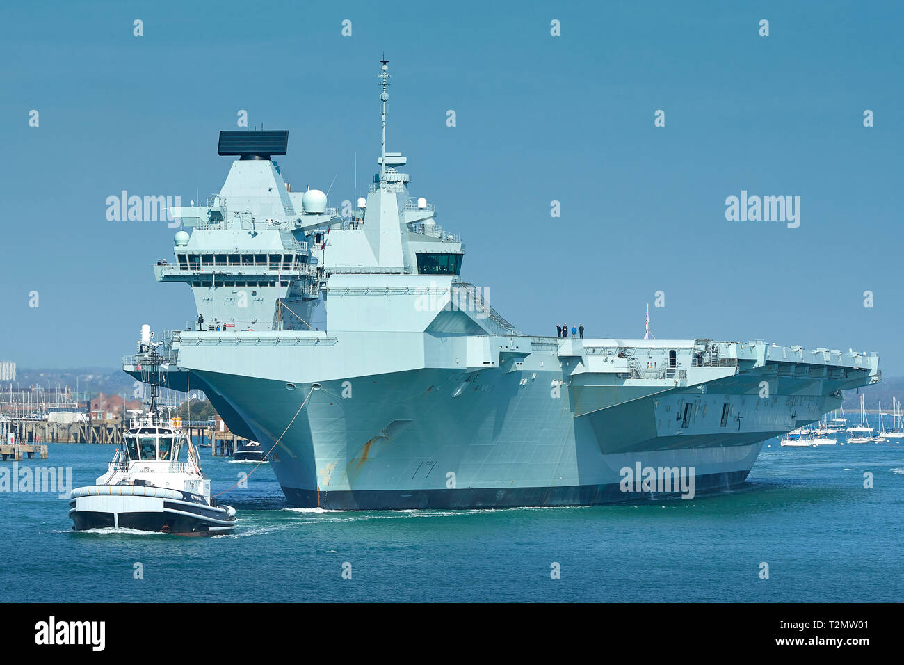 Porte-avions de la Royal Navy, le HMS QUEEN ELIZABETH, étant assisté par un remorqueur, TEMPEST SD comme elle quitte Portsmouth Pour Rosyth, en Écosse. 01 avril 2019. Banque D'Images