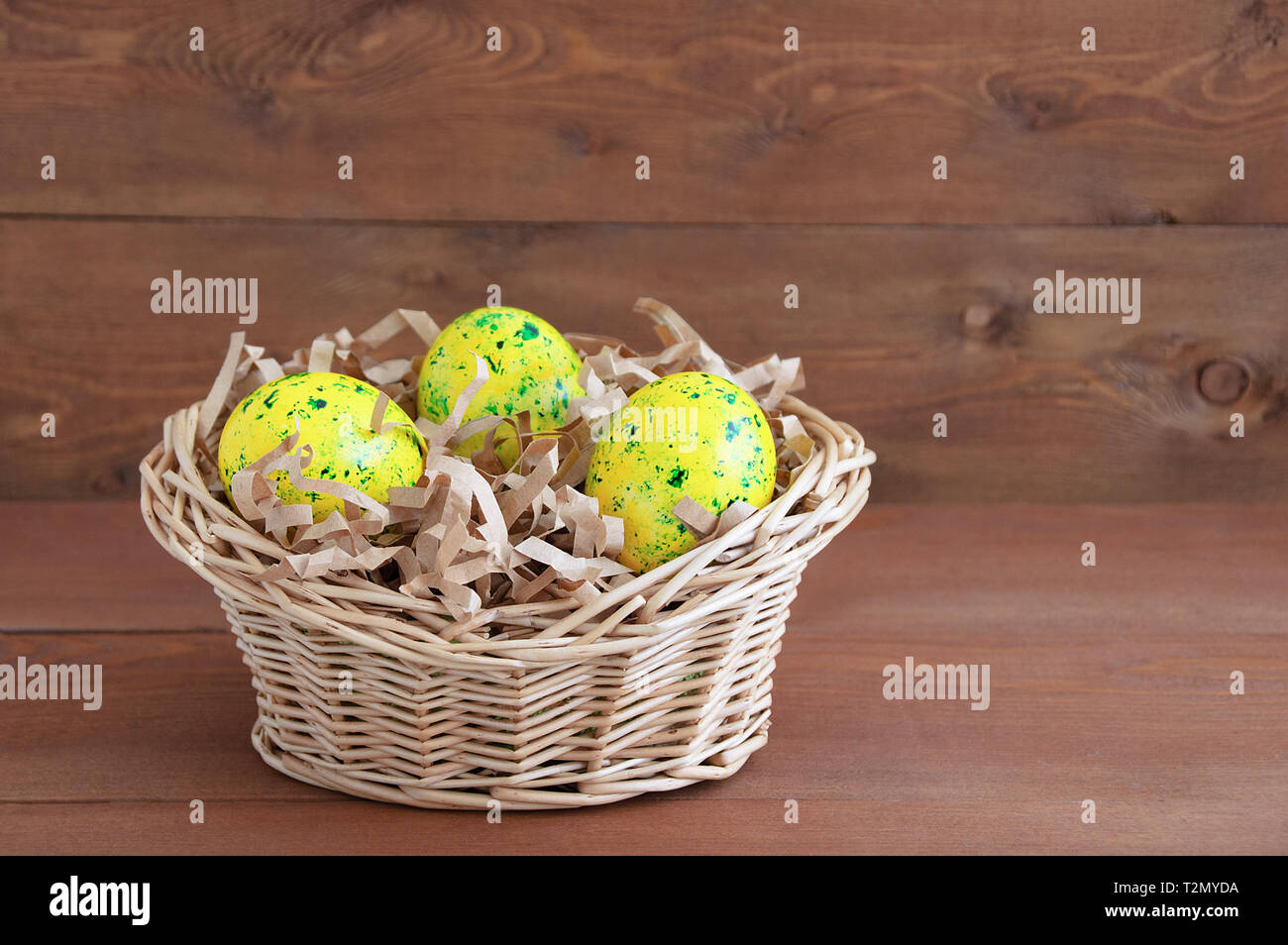Jaune d'œufs de Pâques dans un panier de paille. Sur un fond en bois brun. Close-up. Banque D'Images