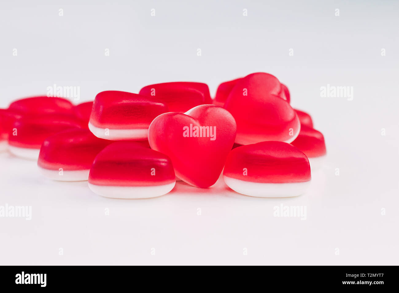 Pile de forme du cœur les bonbons gélatineux rouge et blanc sur fond blanc pour célébrer la Saint-Valentin. Place pour le texte. Banque D'Images