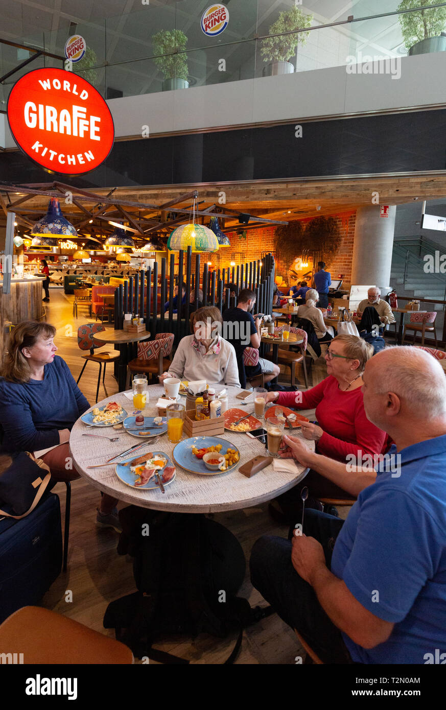 Les gens à manger cuisine monde girafe, terminal intérieur, de départs, de l'aéroport de Malaga, Malaga Espagne Europe Banque D'Images