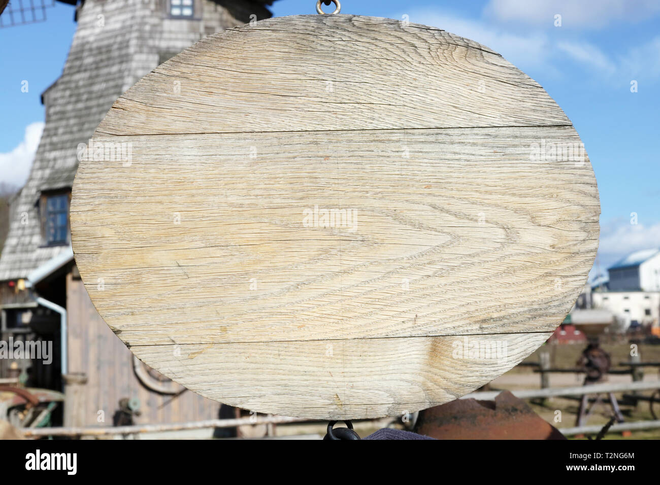 Bannière en bois blanc ovale accroché près d'un vieux moulin. Paysage du printemps Banque D'Images