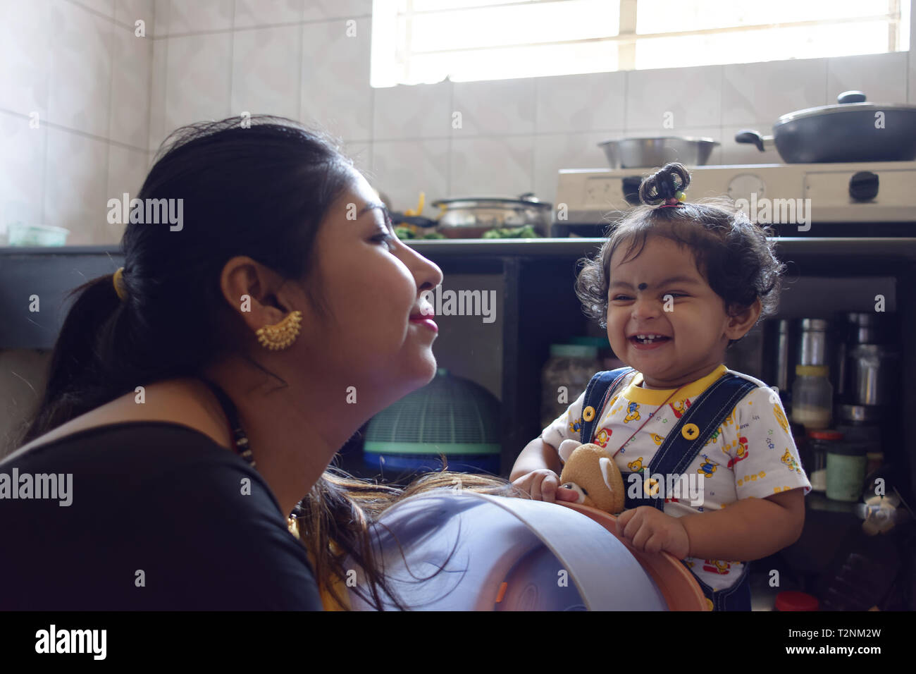 Une belle mère indienne joue avec son bébé fillette dans un environnement accueillant. Banque D'Images