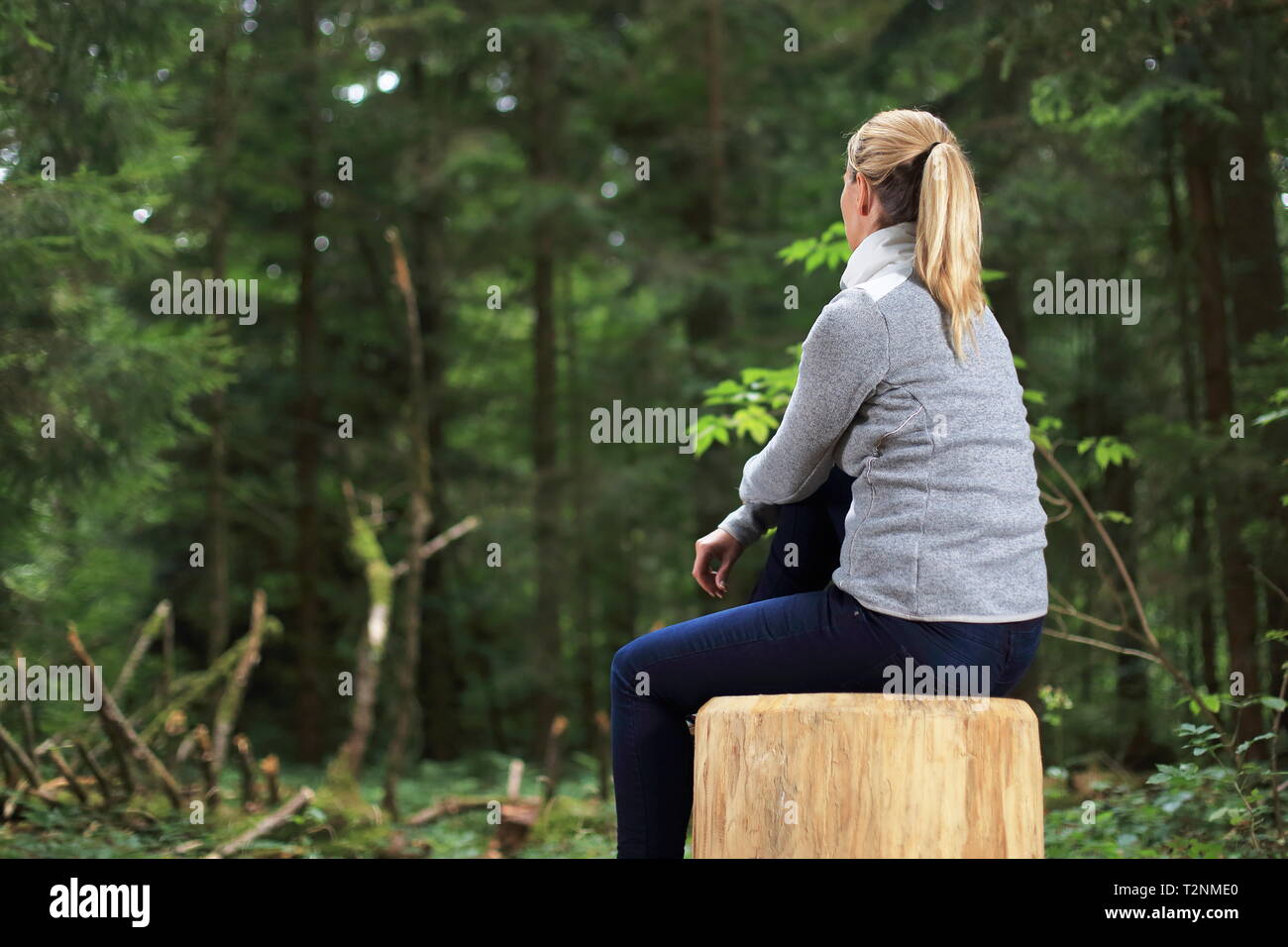 Une femme détendue sur un tronc d'arbre dans une forêt Banque D'Images