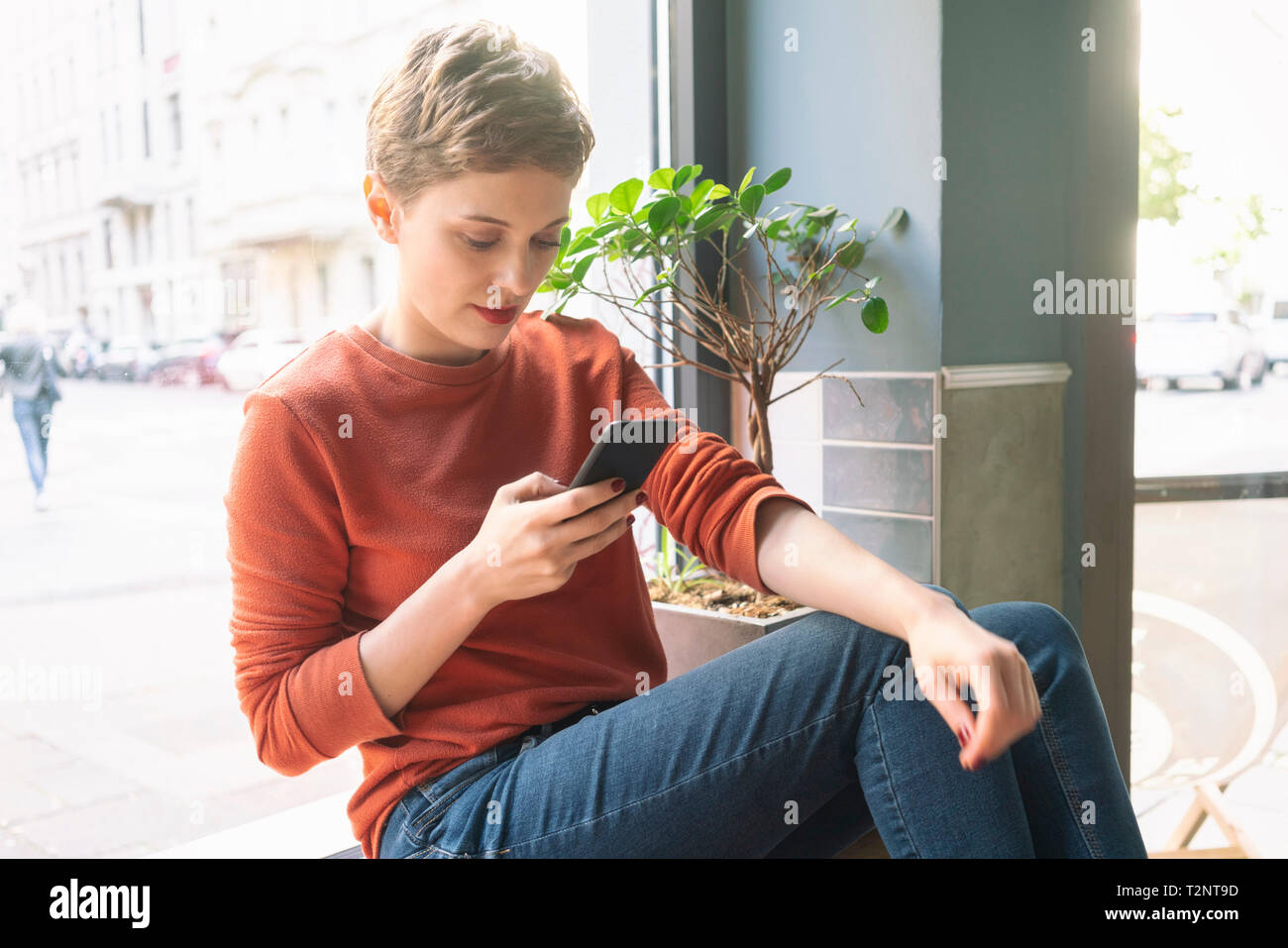 Woman using smartphone à l'intérieur de boutique, Cologne, Nordrhein-Westfalen, Allemagne Banque D'Images