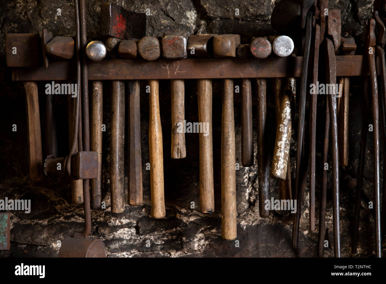 Rangée de marteaux de forgeron et pinces sur mur de l'atelier Banque D'Images