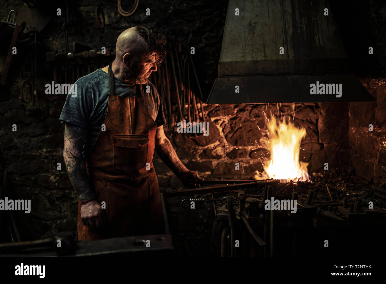 Mâle mature chauffage forgeron metal sur feu ouvert dans l'atelier Banque D'Images