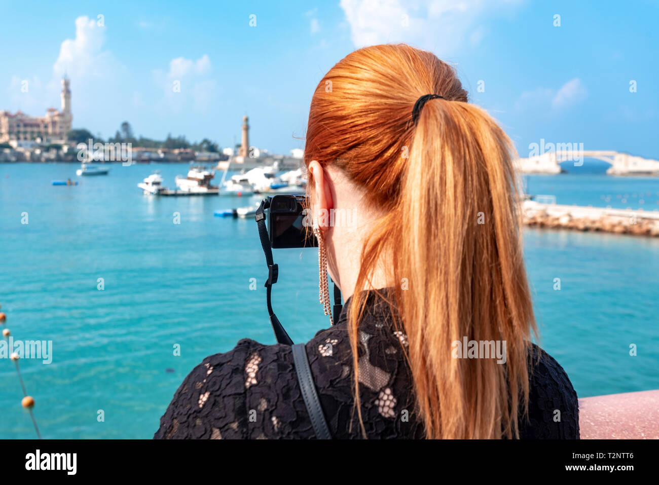Woman with red hair photographier sur mer en direction de Montaza palace, vue arrière, Alexandria, Egypte Banque D'Images