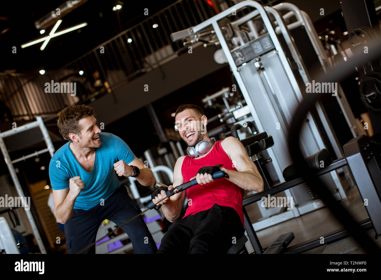 Jeune homme avec trainer faire de l'exercice dans la salle de sport moderne Banque D'Images