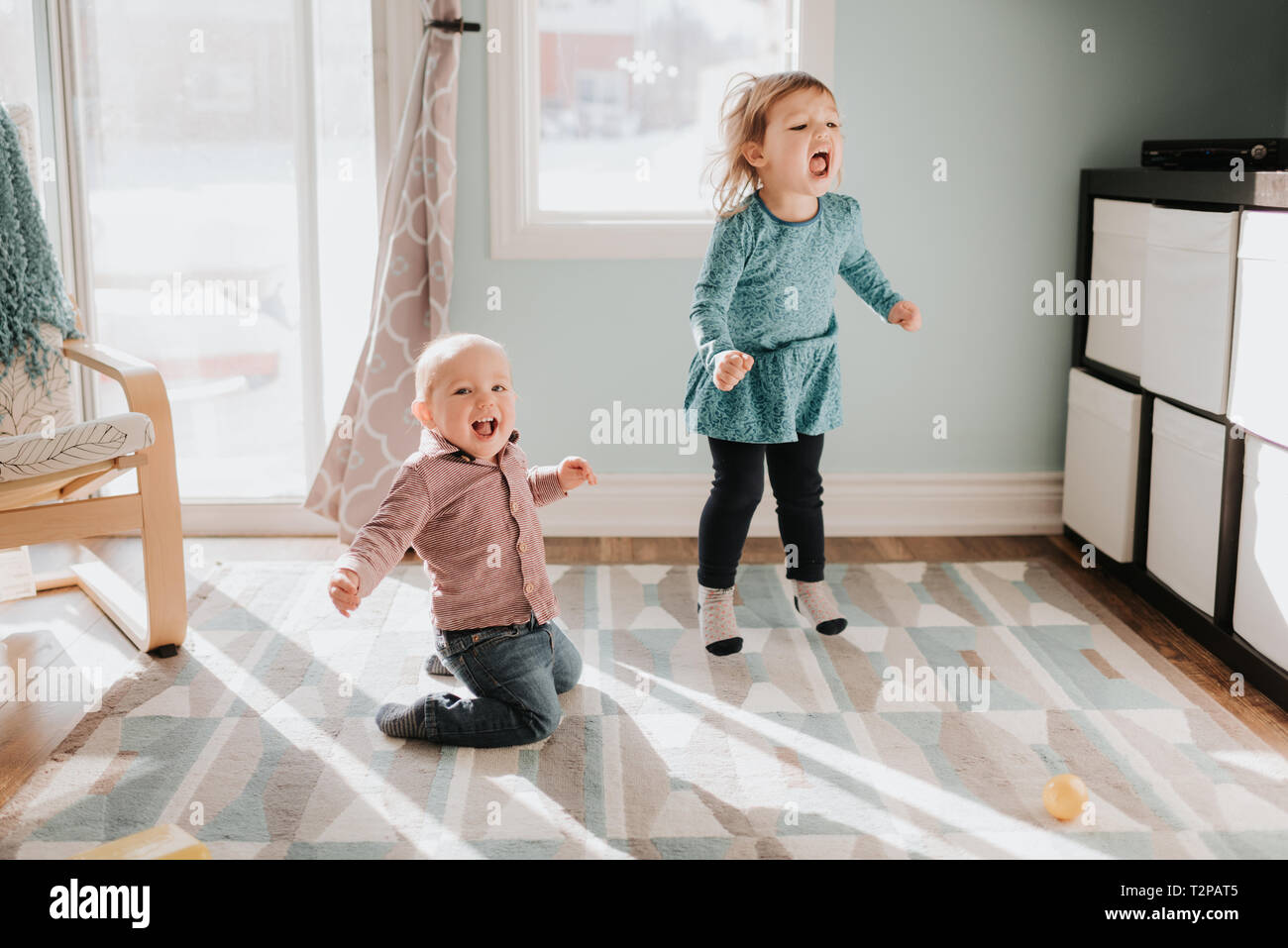 Femme enfant et bébé frère jouant sur des tapis de salon Banque D'Images