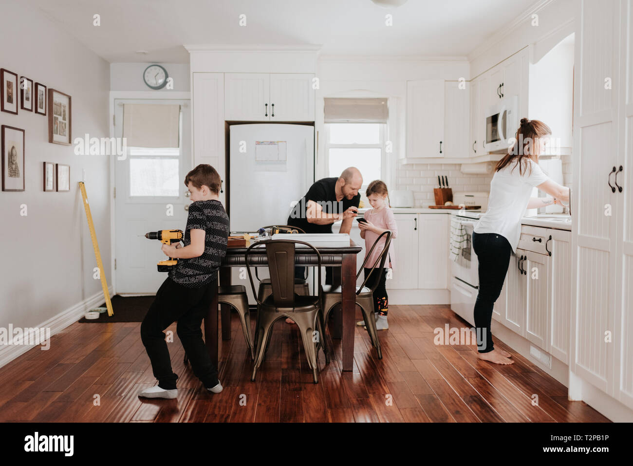 Famille de quatre occupé avec des corvées dans la cuisine Banque D'Images