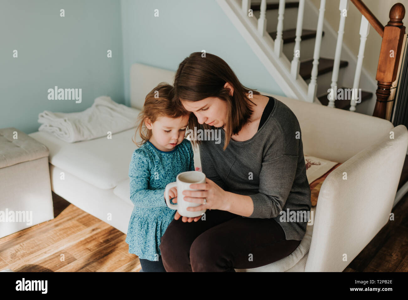 Mère et enfant de sexe féminin à la tasse de café à sur canapé Banque D'Images