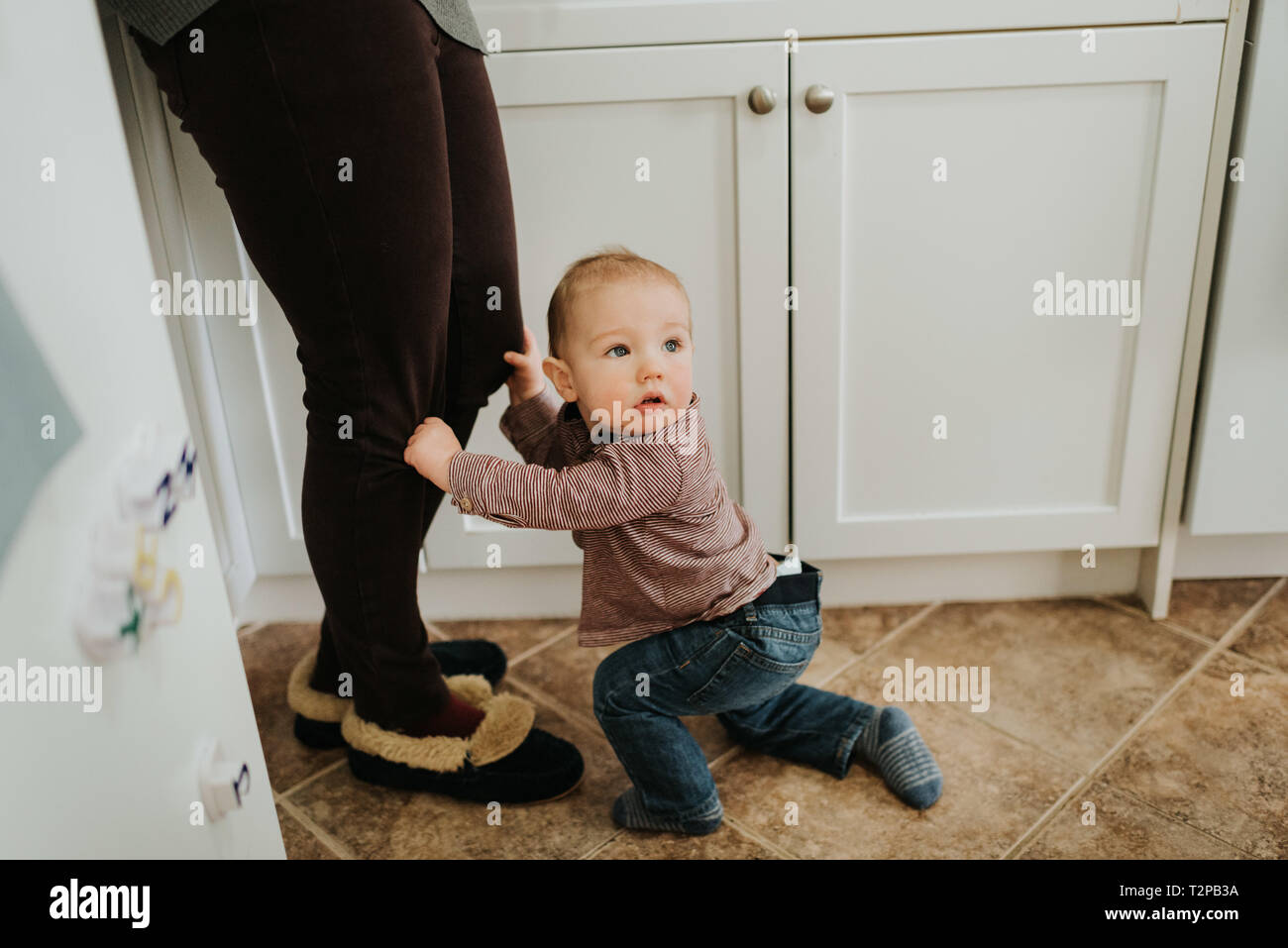 Baby Boy en tenue de cuisine sur les jambes de la mère à Banque D'Images