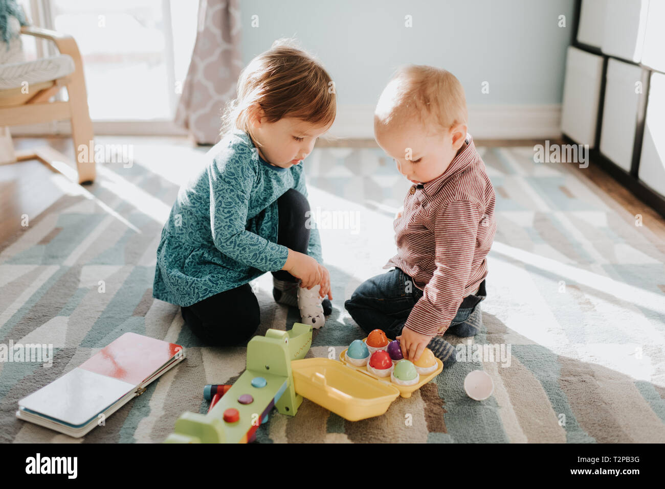 Female toddler Playing with baby brother in living room Banque D'Images