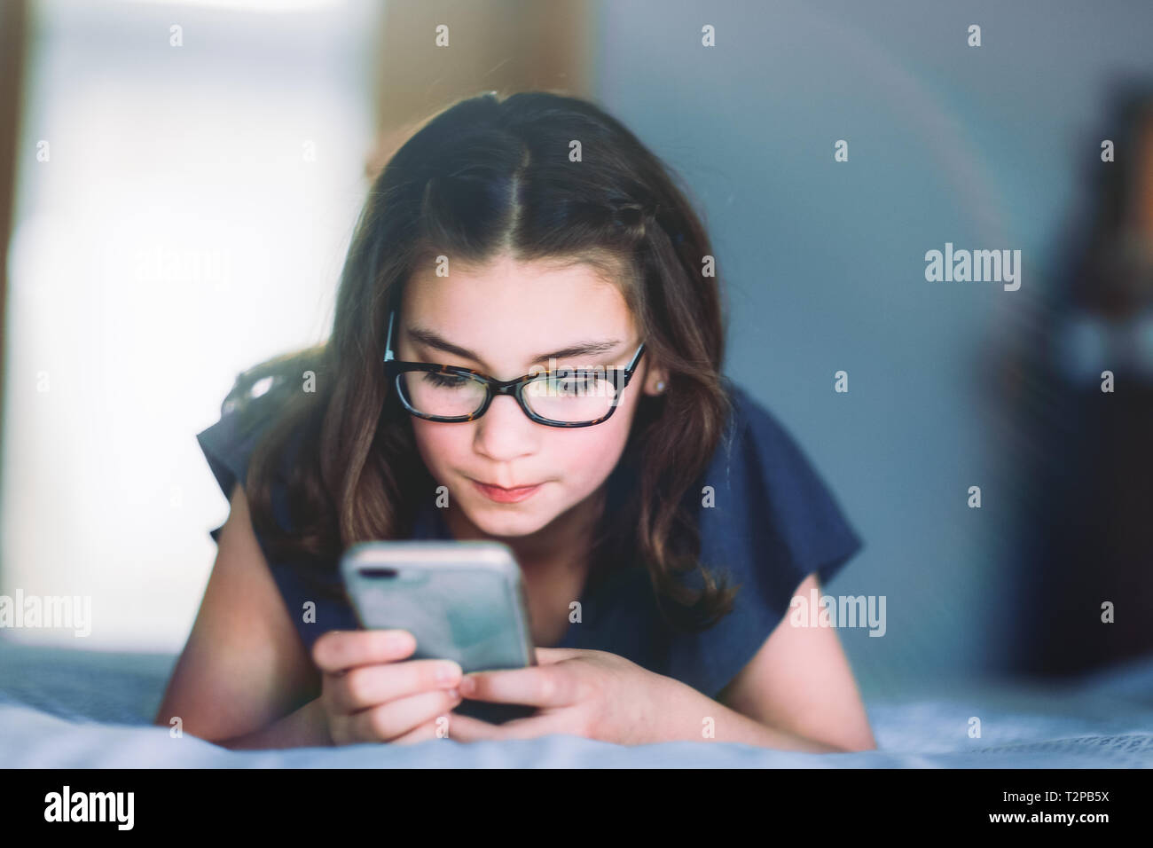 Fille à l'aide du smartphone sur le lit Banque D'Images