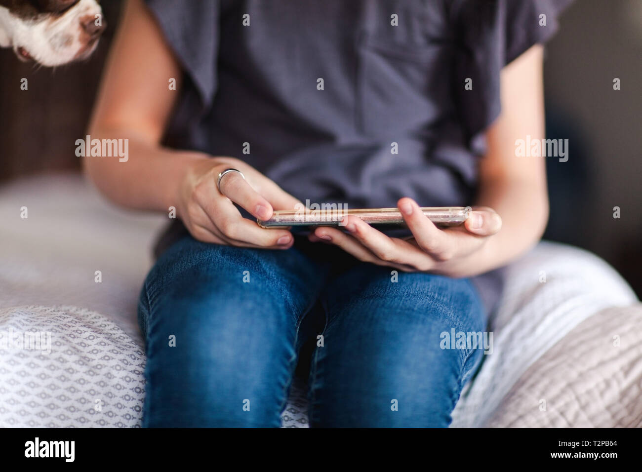 Girl using smartphone à côté de pet dog on bed Banque D'Images