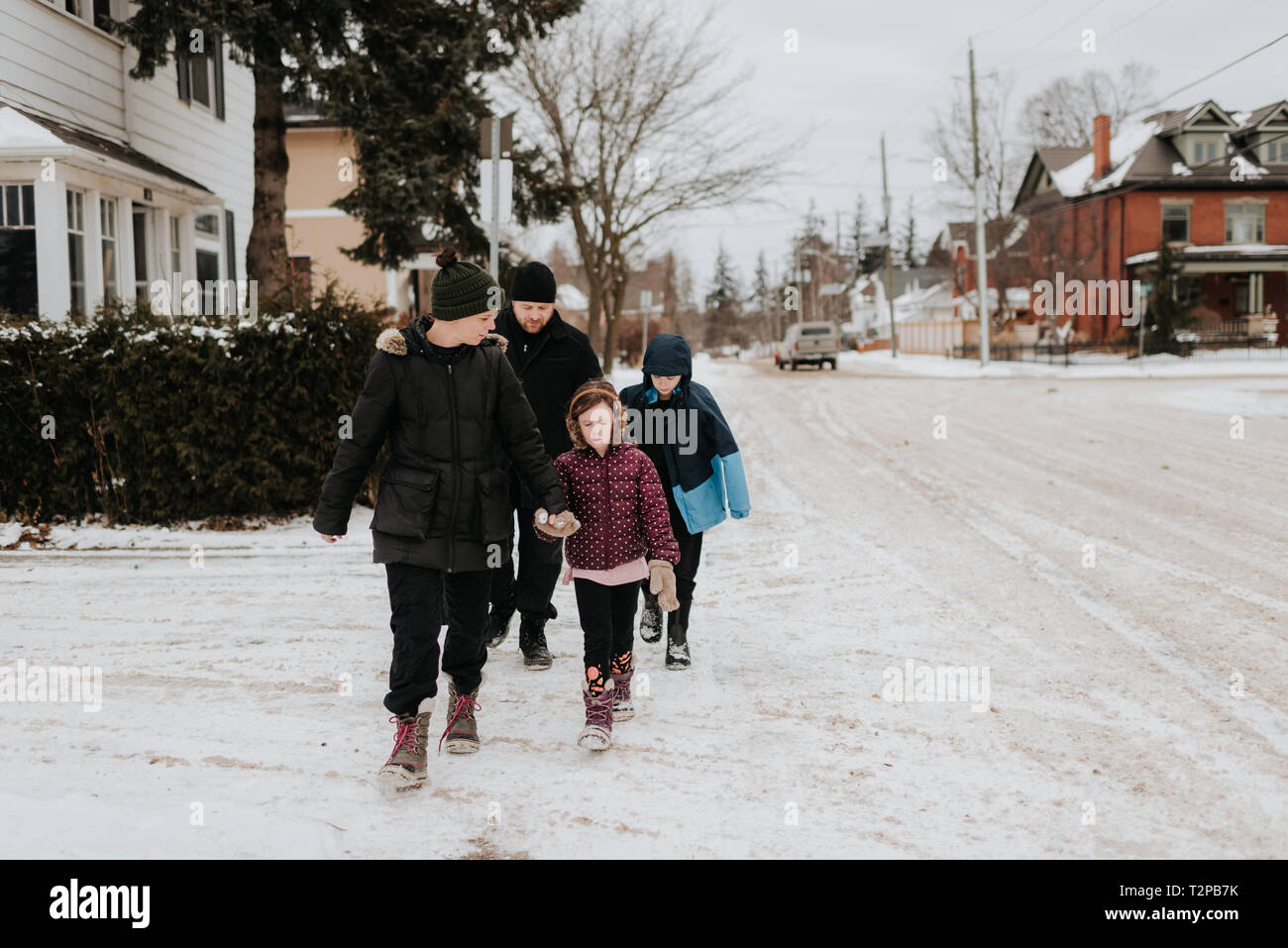 Les parents et les enfants marcher sur rue couverte de neige Banque D'Images