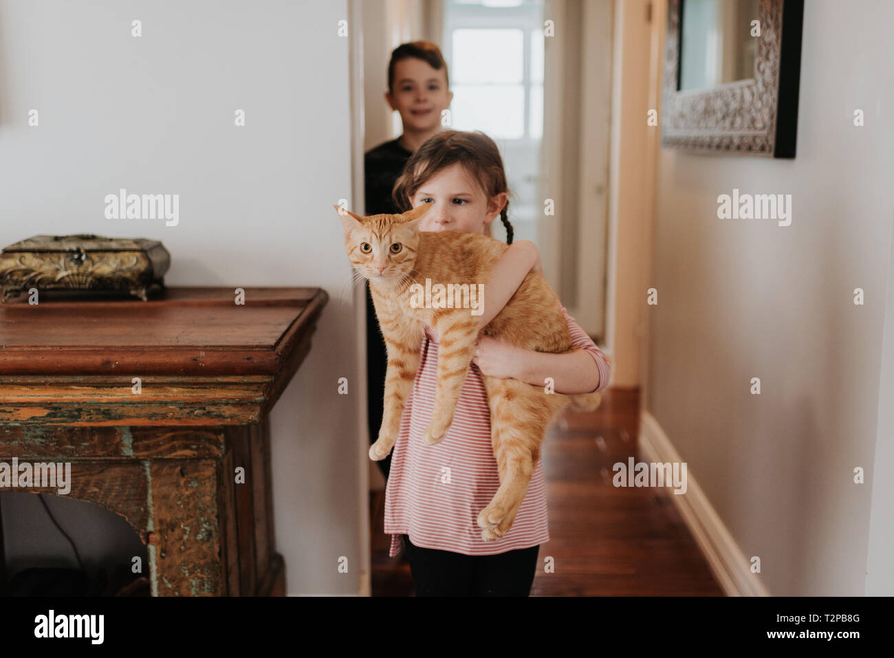 Garçon regardant sœur exerçant son chat à la maison Banque D'Images
