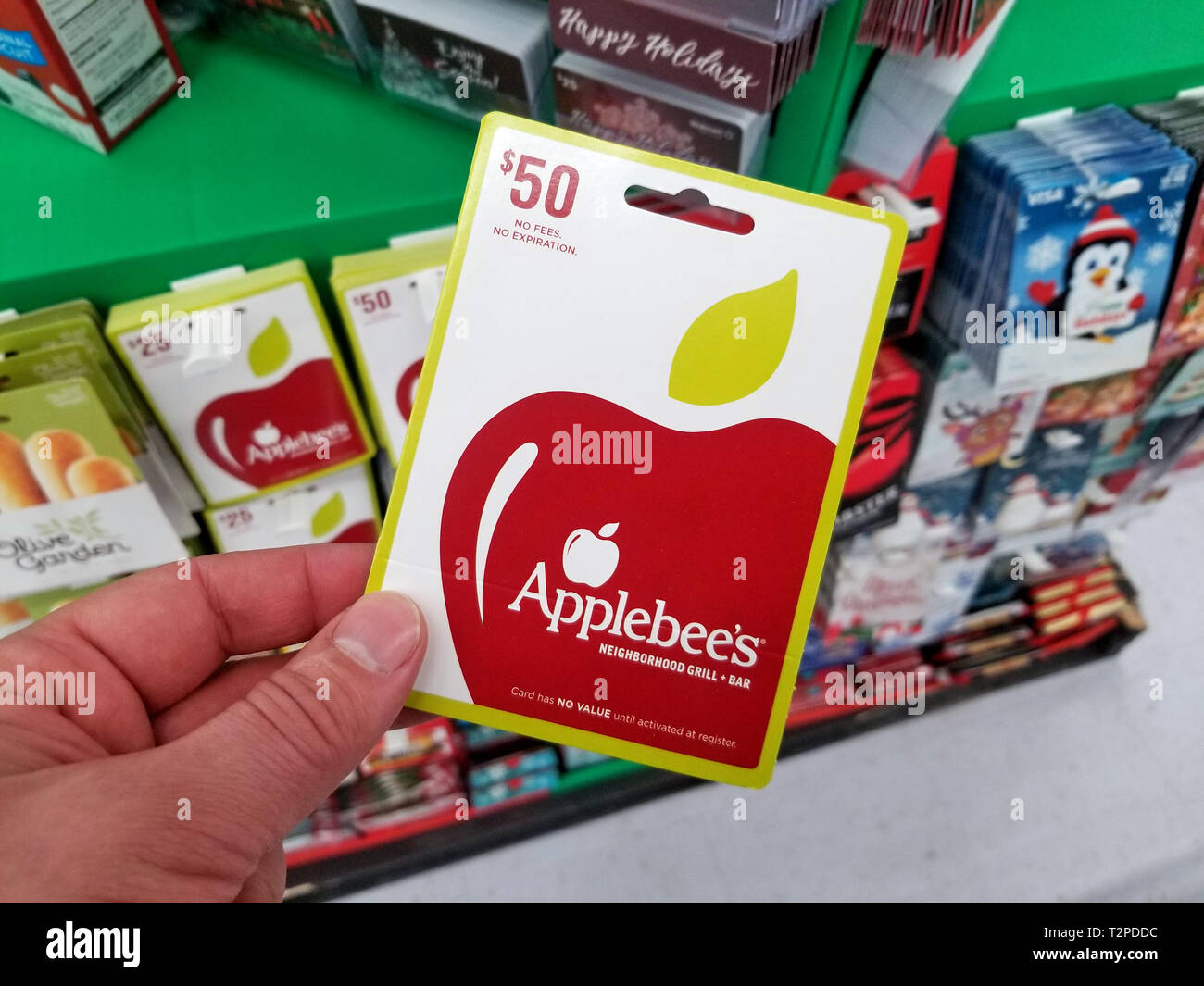 PLATTSBURGH, USA - Le 21 janvier 2019 : Applebees gift card dans une main sur une étagère avec différentes les cartes-cadeaux dans un magasin Walmart. Banque D'Images