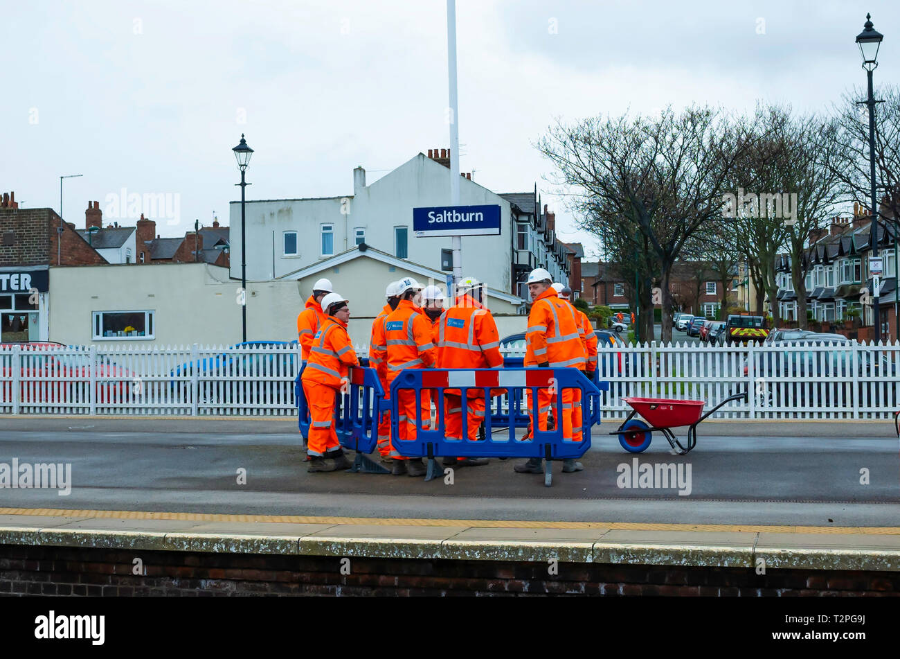 Un gang de l'entretien des chemins de travailleurs en salopette orange discuter un travail sur la plate-forme à Saltburn North Yorkshire Banque D'Images