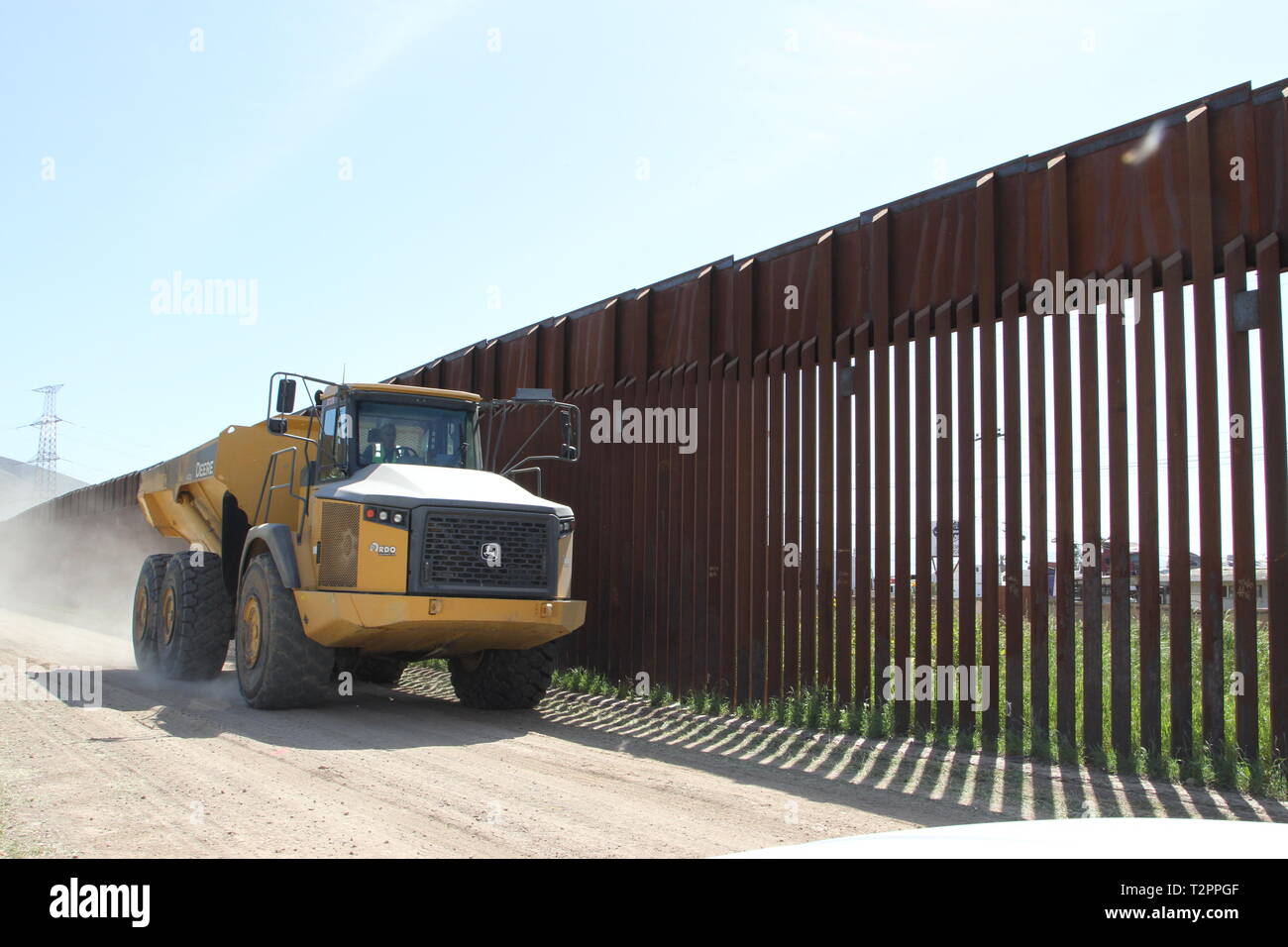 A 13-foot-tall dump truck tire de creuser les débris en face de 18 pieds de haut mur frontière primaire de San Diego le 29 mars 2019. Le corps est en appui au Ministère de la sécurité intérieure en vue de bâtir de nouvelles mur frontière près de San Diego. Banque D'Images