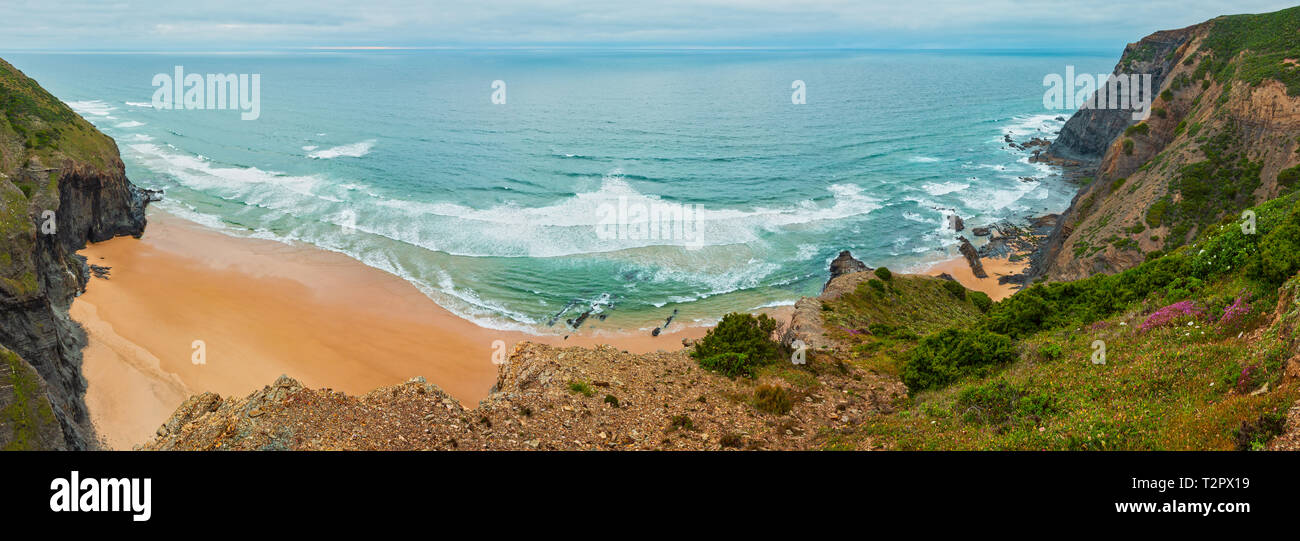 Plage de sable avec des crêtes pierreuses temps couvert vue sur la côte rocheuse de l'Atlantique d'été (Costa Vicentina, Algarve, Portugal). Ocean Surf et vagues. Banque D'Images