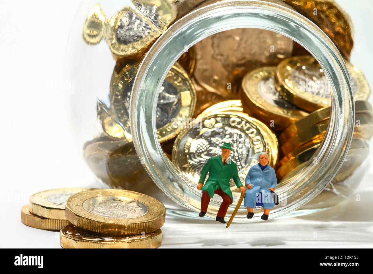 Droit des personnes âgées diorama conceptuel figures miniatures s'assit sur le rebord d'un bocal en verre rempli de pièces livre Banque D'Images