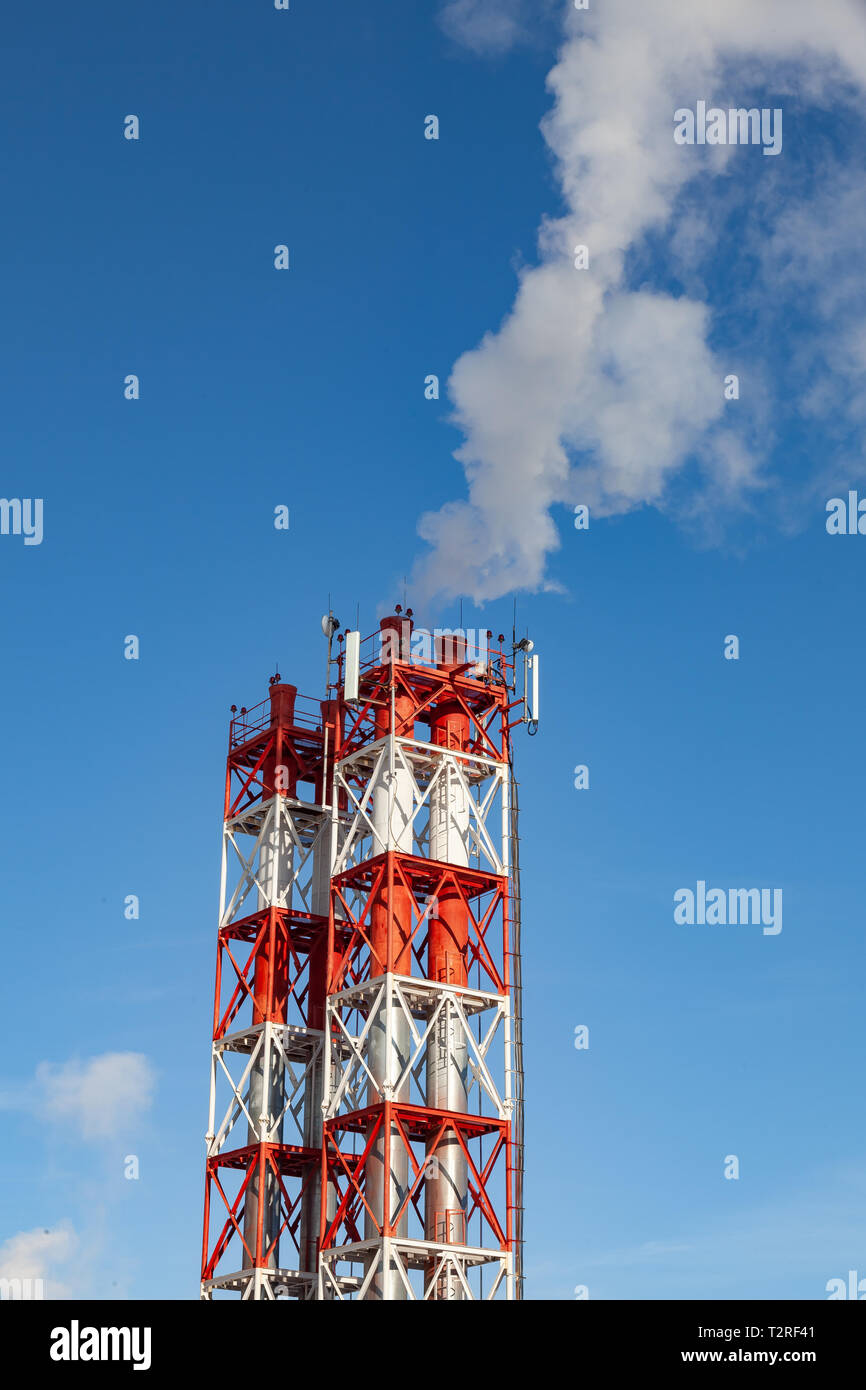 White fumée nocive provenant de la croix rouge et blanc avec des tuyaux d'antennes de communication mobile dans une usine dans le centre-ville dans le contexte de Banque D'Images