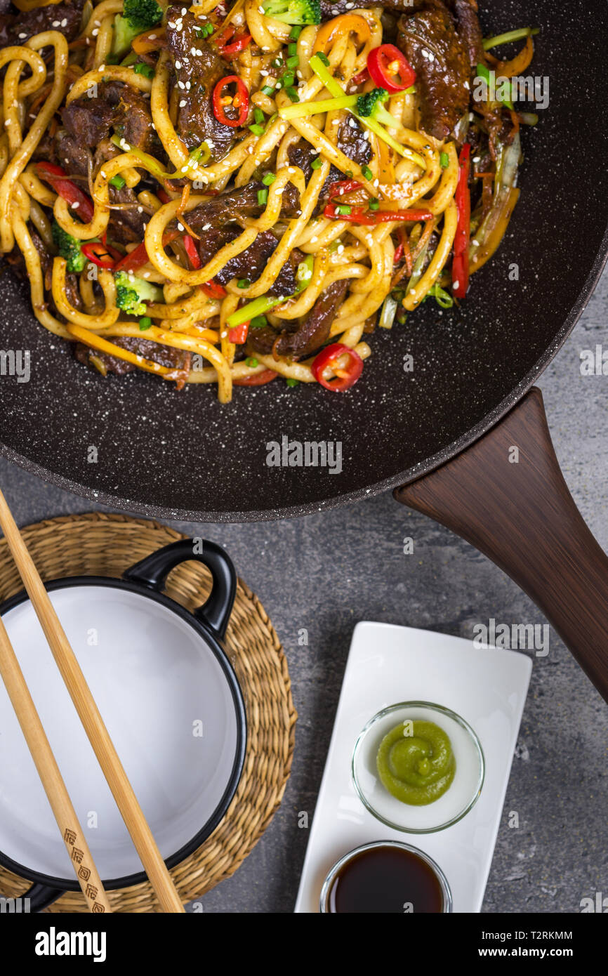 Udon Nouilles sauté au Bœuf et légumes au wok casserole sur fond sombre Banque D'Images