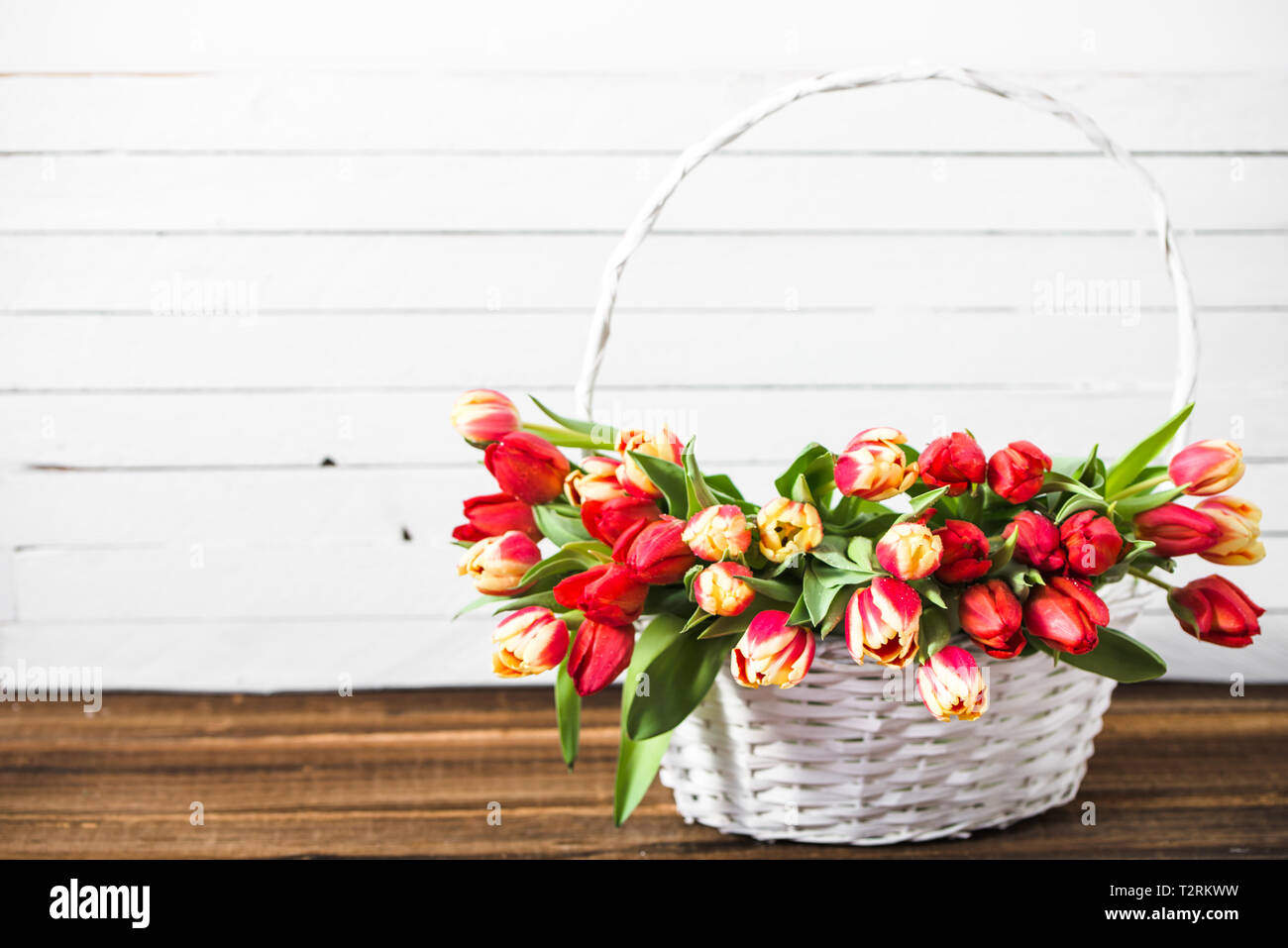 Bouquet de tulipes dans un panier sur la table en bois. Fleurs fête des mères. Banque D'Images