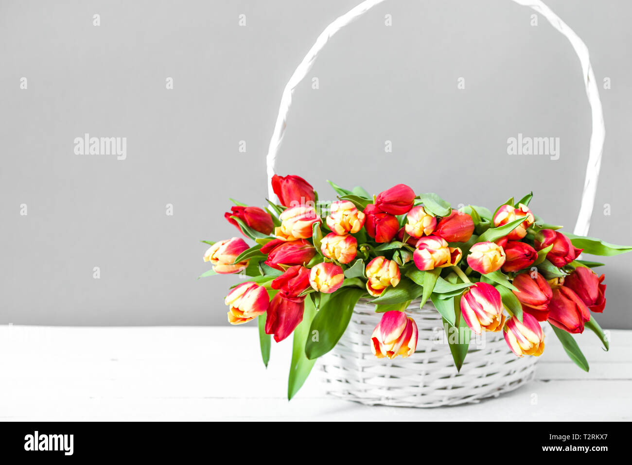 Panier avec bouquet de tulipe. Pâques Printemps fleurs sur fond jaune. Cadeau de la fête des mères. Banque D'Images