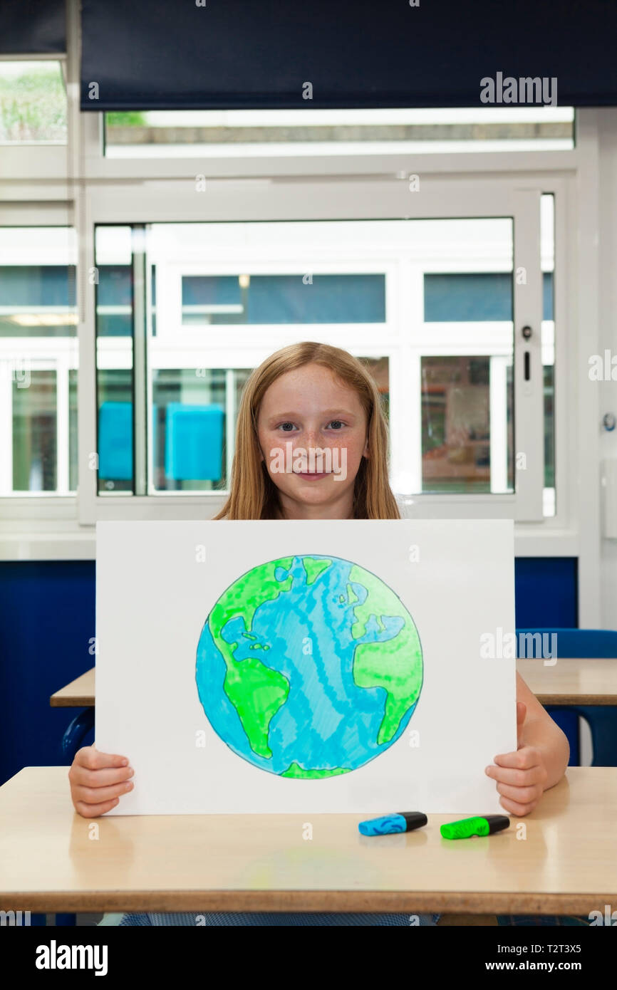 L'école primaire caucasian girl holding placard avec une image de la terre Banque D'Images