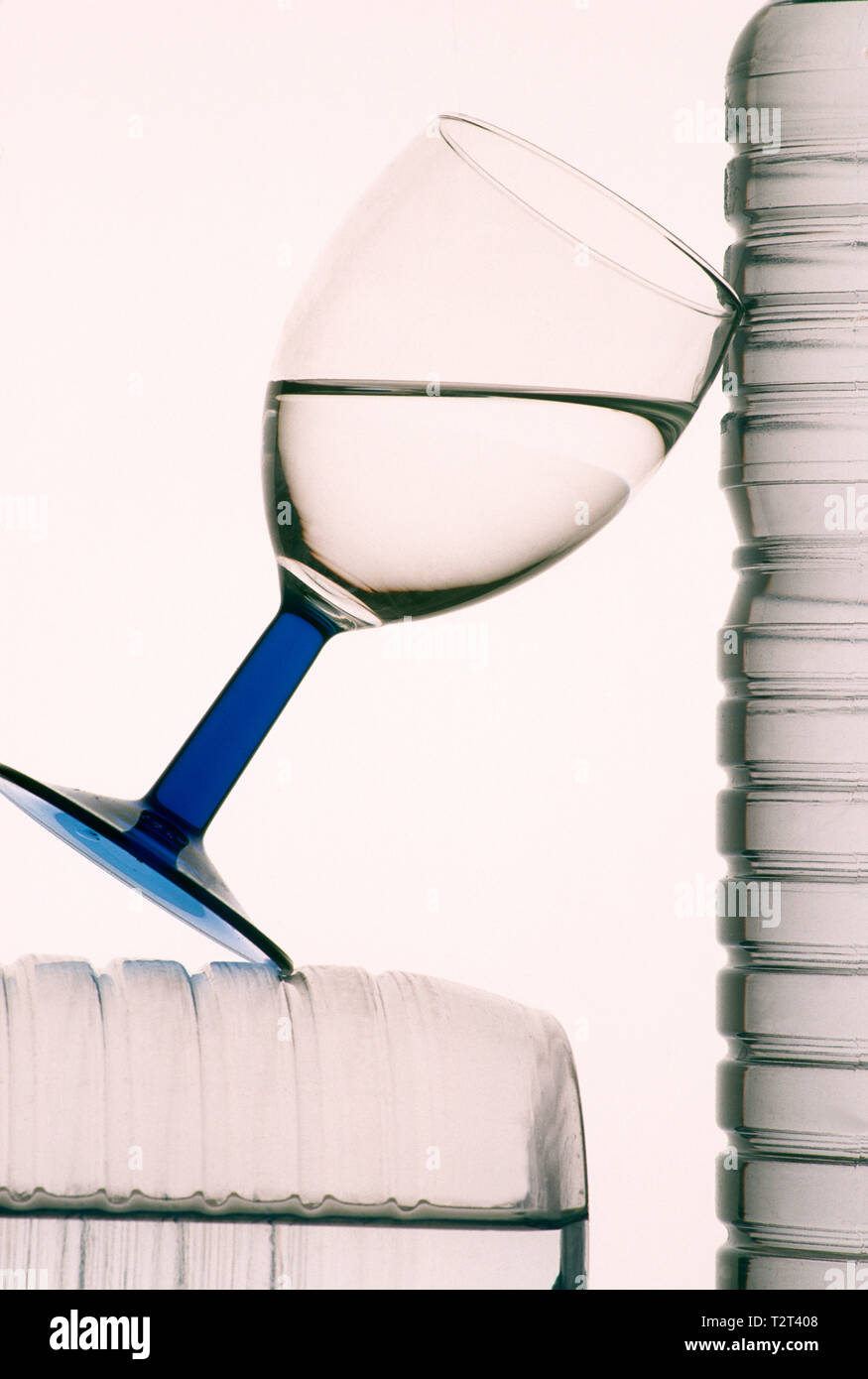 Plan vertical d'un verre d'eau entre deux bouteilles en plastique avec un fond blanc Banque D'Images